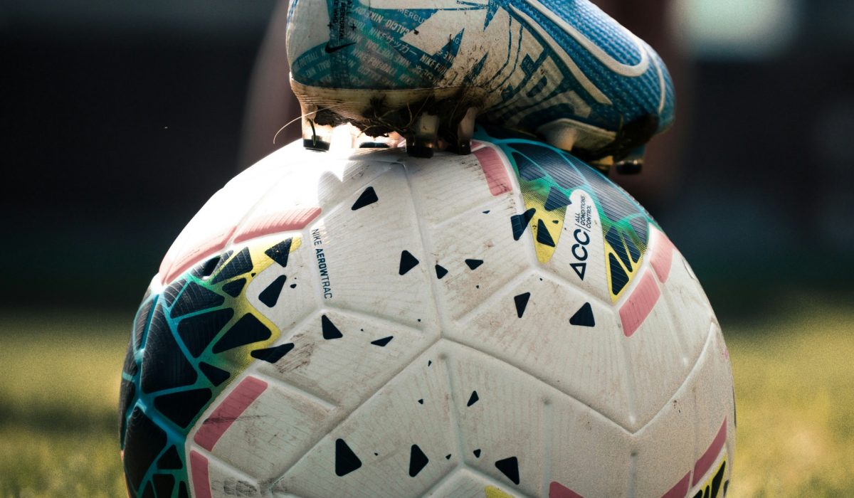 Image of a foot on a football, it shows the sport and a sporty figure.
