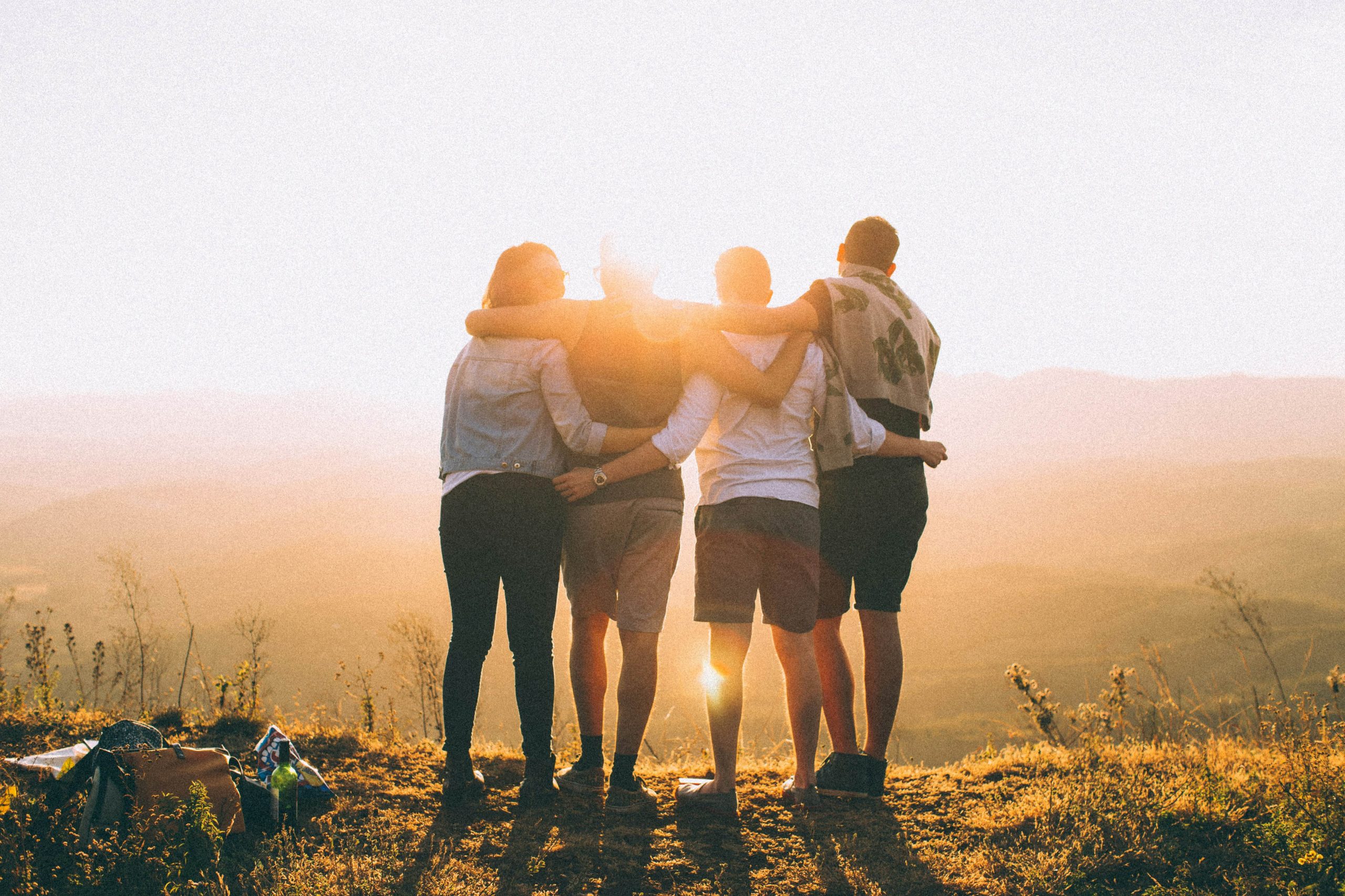 Image of four friends, who're having a great time together at sunset, their friendship is strong.